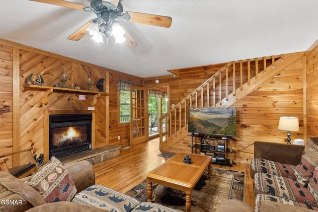 2112 Redmond Way, Sevierville, TN 37876 - living area with wood walls, stairway, wood finished floors, ceiling fan, and a warm lit fireplace