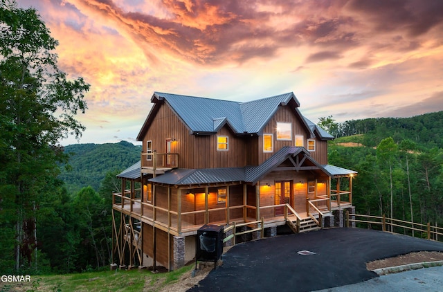 2741 Red Sky Dr, Sevierville, TN 37862 - rustic home featuring a metal roof, a wooded view, board and batten siding, and covered porch