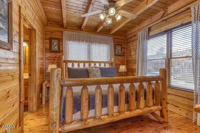 bedroom with multiple windows, wood walls, beamed ceiling, and wood ceiling