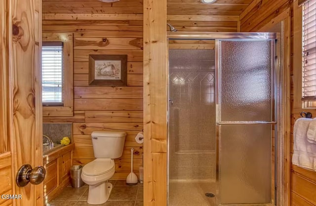 bathroom with tile patterned floors, wood walls, a shower with shower door, and toilet