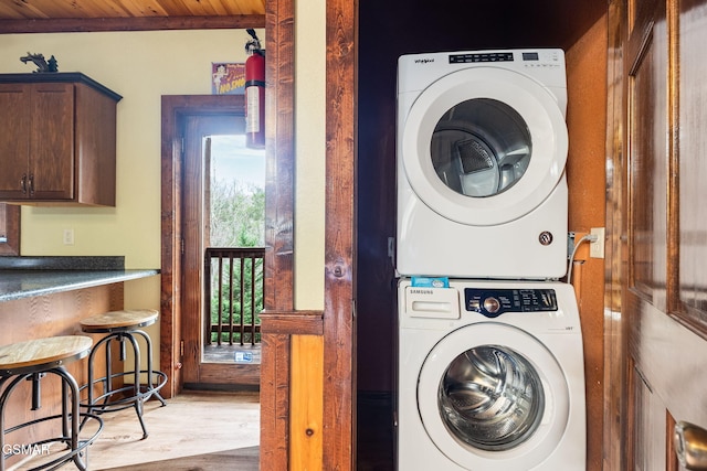 laundry room with wood ceiling, light wood-type flooring, and stacked washer / drying machine