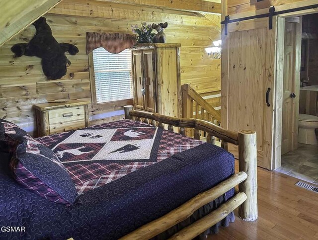1554 Bear Valley Rd, Sevierville, TN 37876 - bedroom with wooden walls, wood finished floors, a barn door, and ensuite bathroom