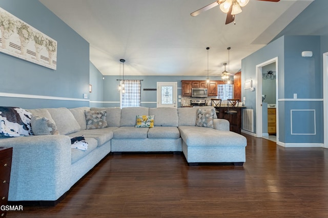 living room with ceiling fan with notable chandelier and dark hardwood / wood-style flooring