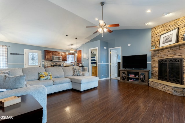 living room with vaulted ceiling, dark hardwood / wood-style floors, a fireplace, and ceiling fan