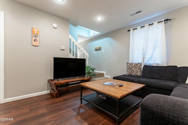 living room featuring dark wood-type flooring and a skylight