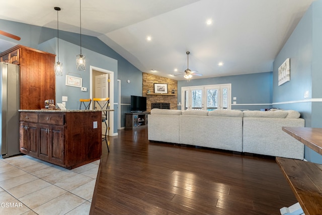 living room with ceiling fan, lofted ceiling, a fireplace, and light hardwood / wood-style flooring