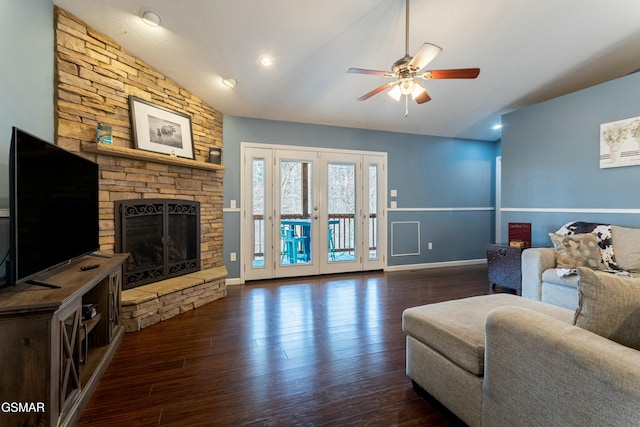 living room featuring ceiling fan, lofted ceiling, dark hardwood / wood-style flooring, and a stone fireplace