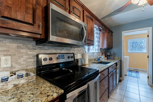 kitchen featuring sink, light tile patterned floors, appliances with stainless steel finishes, light stone counters, and decorative backsplash