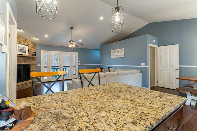 kitchen featuring vaulted ceiling, a stone fireplace, ceiling fan, dark wood-type flooring, and french doors