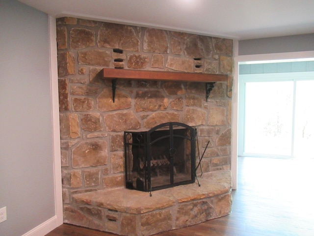 room details with hardwood / wood-style floors and a stone fireplace