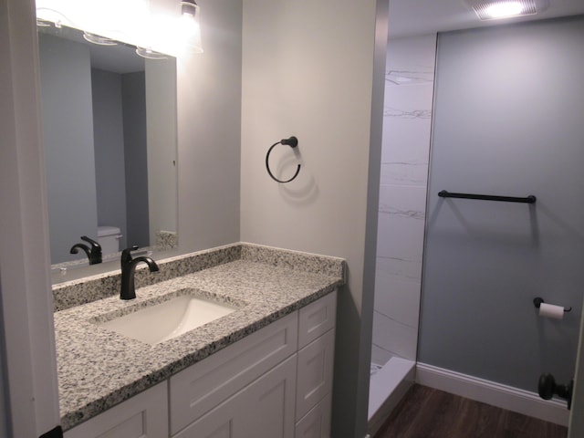 bathroom featuring a shower, vanity, hardwood / wood-style flooring, and toilet