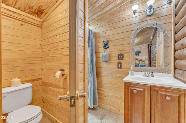 full bath featuring wooden walls, vanity, and toilet