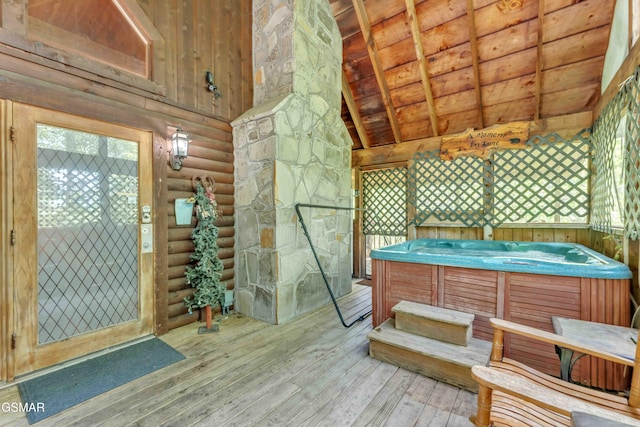 interior space with lofted ceiling with beams, hardwood / wood-style floors, a jacuzzi, wooden ceiling, and log walls