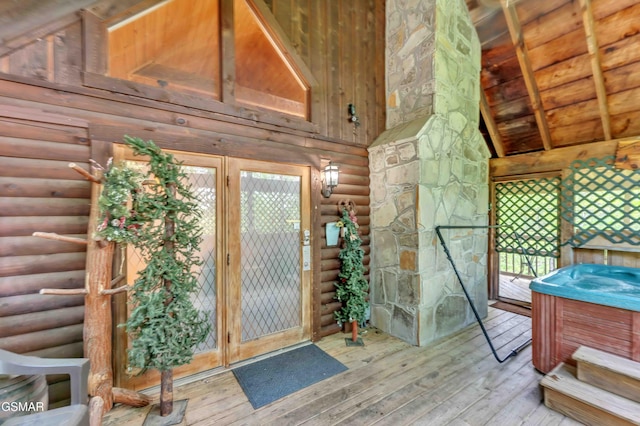 doorway featuring log walls, wood-type flooring, and a towering ceiling