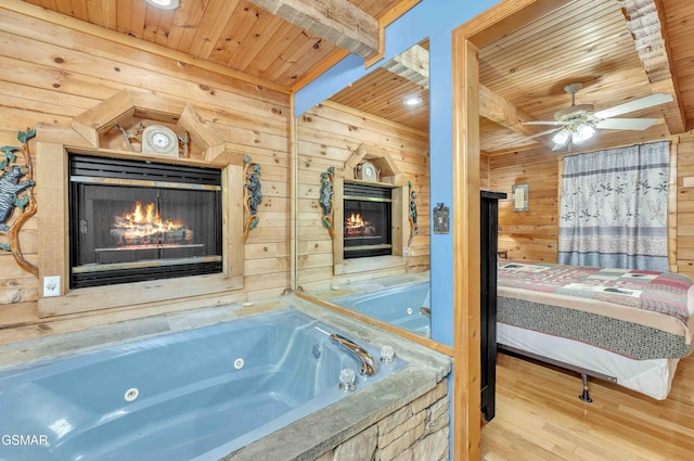 full bathroom with wood ceiling, beam ceiling, a warm lit fireplace, and wooden walls
