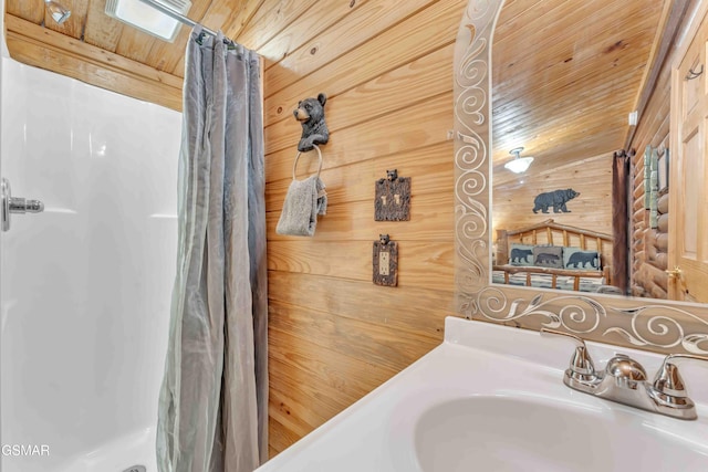 bathroom featuring wooden walls, a sink, wooden ceiling, and curtained shower