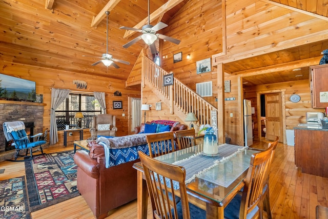 dining room with stairway, wooden ceiling, a stone fireplace, and light wood finished floors