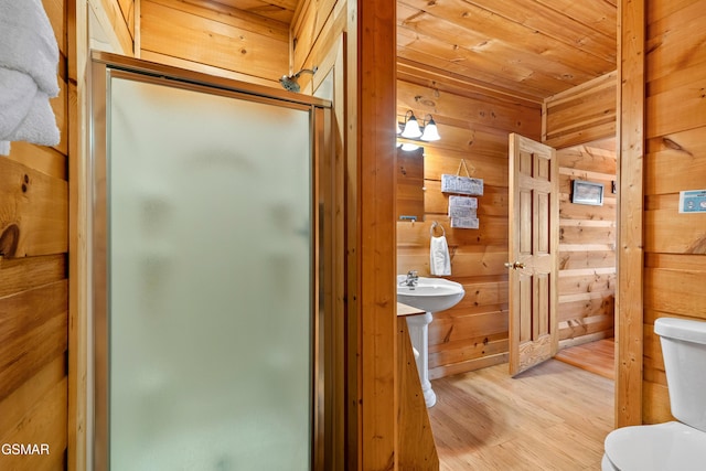 full bath featuring toilet, wood ceiling, wood walls, a shower stall, and wood finished floors