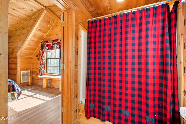 interior space with lofted ceiling, visible vents, wood ceiling, wood walls, and wood finished floors