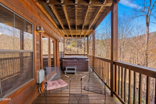 deck featuring a view of trees and a hot tub