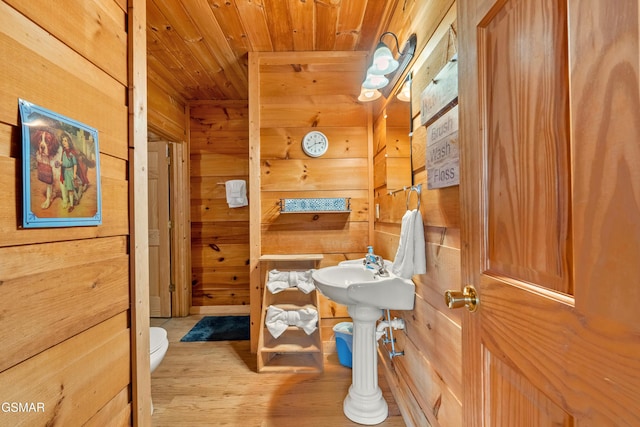 half bathroom featuring wood walls, wooden ceiling, wood finished floors, and toilet