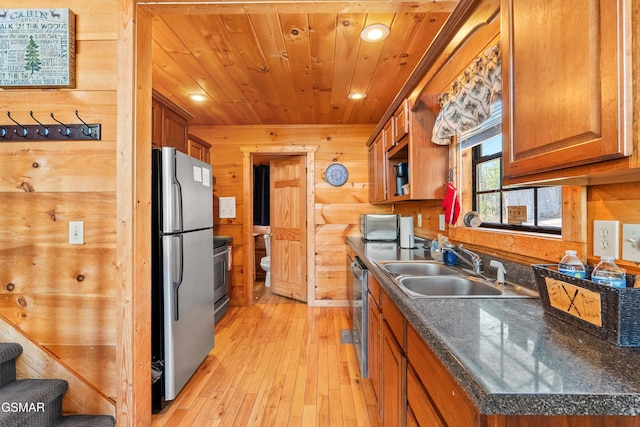 kitchen with wooden ceiling, wooden walls, a sink, and freestanding refrigerator