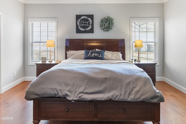 bedroom with ornamental molding, light hardwood / wood-style flooring, and multiple windows