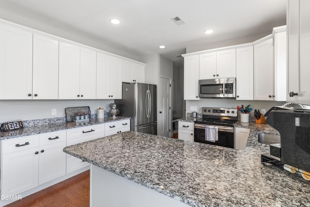 kitchen with white cabinets, appliances with stainless steel finishes, and dark stone countertops