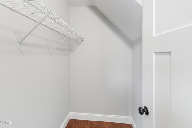 walk in closet with wood-type flooring and vaulted ceiling