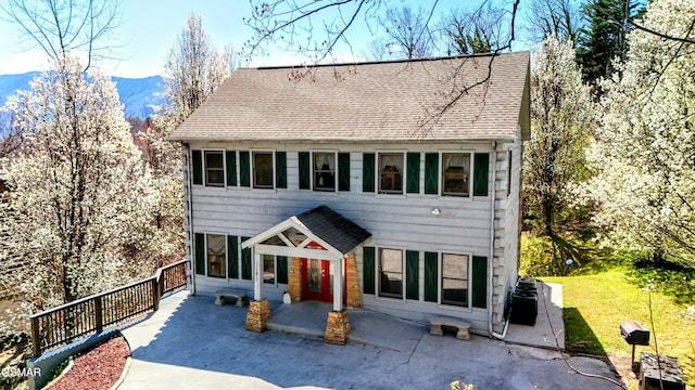 view of front of home with a mountain view, a patio, and a shingled roof