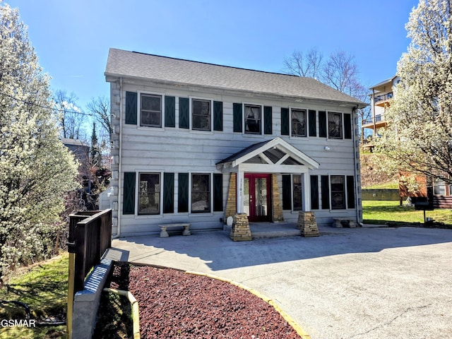 colonial-style house featuring french doors, a shingled roof, and a patio area