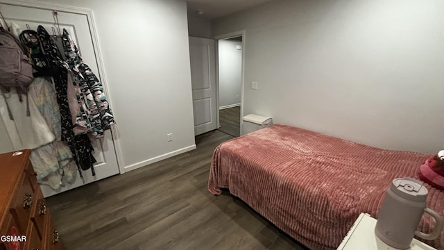 bedroom with dark wood-type flooring and baseboards