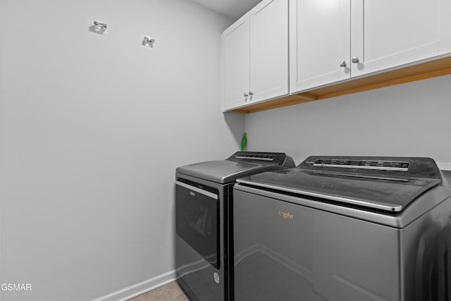 clothes washing area featuring baseboards, light tile patterned floors, cabinet space, and washing machine and dryer
