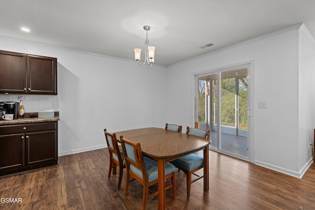 dining room with dark wood finished floors, visible vents, a chandelier, and crown molding