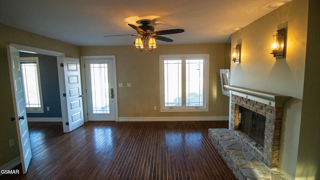 unfurnished living room featuring ceiling fan, a fireplace, and dark wood-type flooring