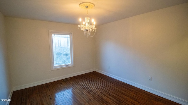 empty room featuring dark wood-type flooring and a chandelier