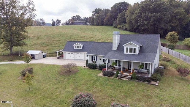 cape cod home featuring an outbuilding, covered porch, a front yard, and a garage