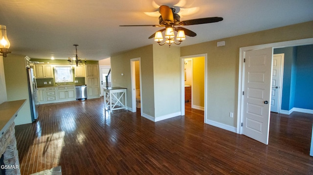 unfurnished living room with ceiling fan with notable chandelier, sink, and dark wood-type flooring