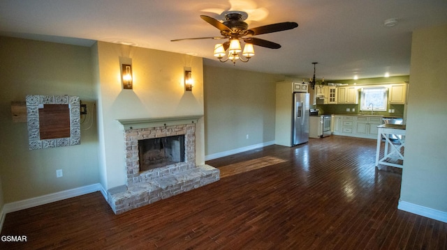 unfurnished living room with ceiling fan, sink, dark hardwood / wood-style floors, and a brick fireplace