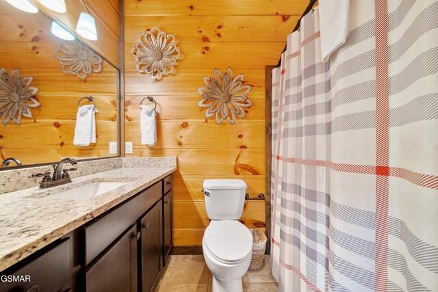 bathroom with toilet, tile patterned floors, wooden walls, and vanity