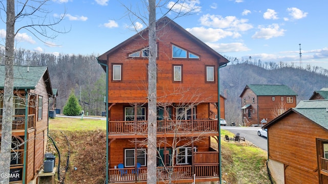 back of property with central AC, a porch, and a mountain view