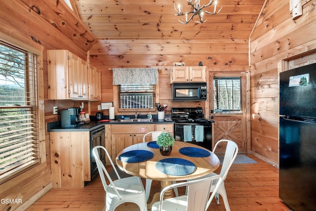 kitchen with vaulted ceiling, wood walls, light brown cabinetry, and black appliances