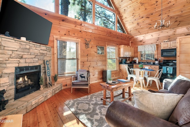 living room featuring a stone fireplace, wood walls, high vaulted ceiling, light wood-type flooring, and sink