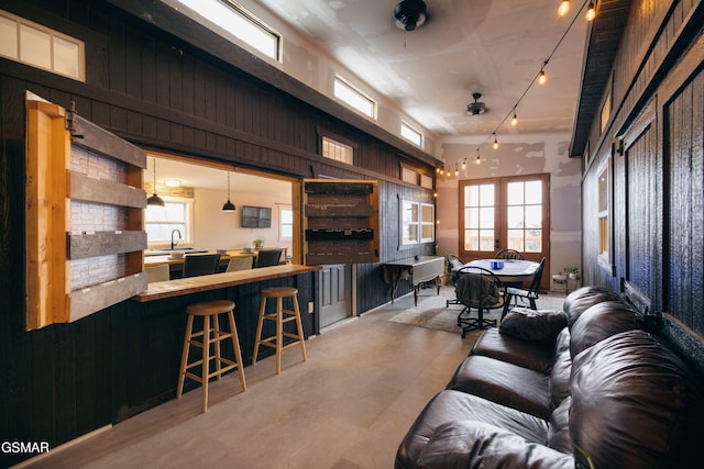 living room with sink, a high ceiling, and wood walls