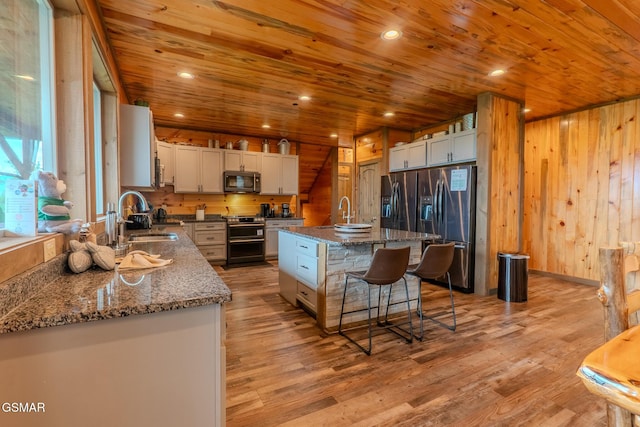2414 Hackberry Dr, Sevierville, TN 37862 - kitchen with appliances with stainless steel finishes, wooden ceiling, a kitchen breakfast bar, dark stone counters, and light wood finished floors