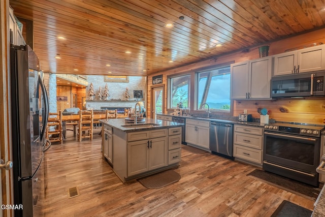 2414 Hackberry Dr, Sevierville, TN 37862 - kitchen with appliances with stainless steel finishes, wooden ceiling, light wood-type flooring, a center island with sink, and dark stone counters