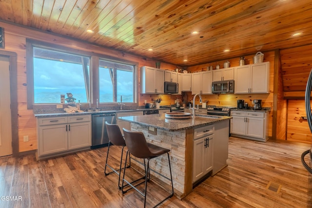 2414 Hackberry Dr, Sevierville, TN 37862 - kitchen featuring appliances with stainless steel finishes, a breakfast bar, light wood finished floors, an island with sink, and wooden ceiling