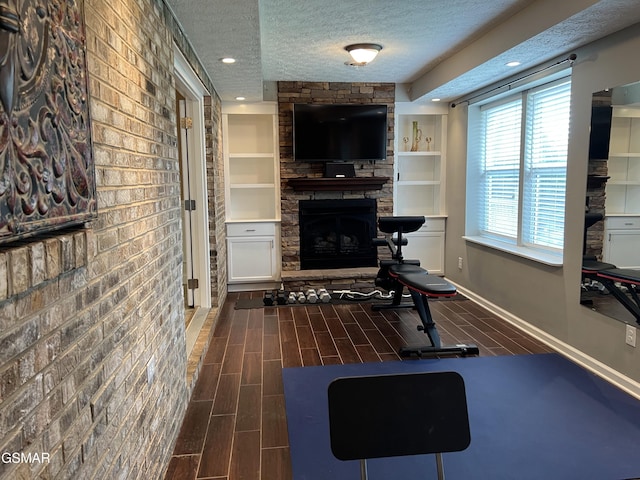 1018 Southwind Cir, Dandridge, TN 37725 - exercise room featuring a textured ceiling, a fireplace, built in shelves, and dark wood-style flooring