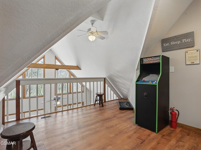 interior space featuring wood finished floors, visible vents, lofted ceiling, ceiling fan, and a textured ceiling