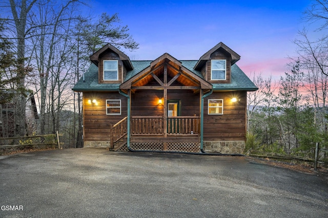 chalet / cabin featuring a porch and a shingled roof